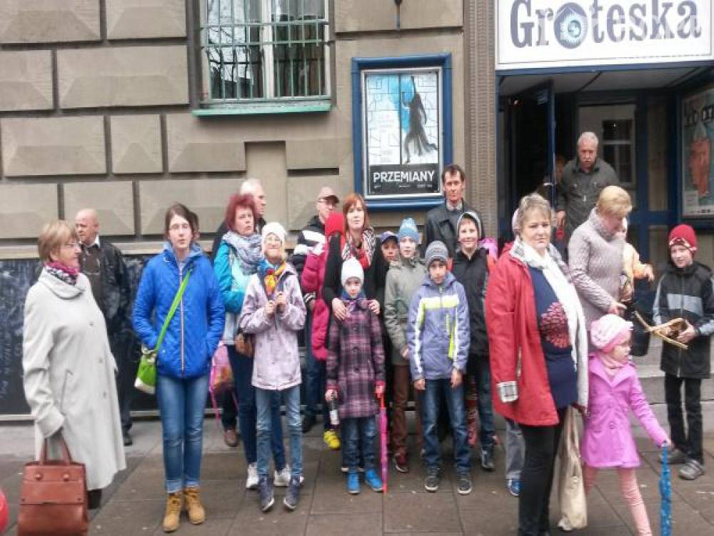 Zdjęcie: Grupa uczestników i uczestniczek projektu wraz z dziećmi stojąca przed wejściem do Teatru Groteska